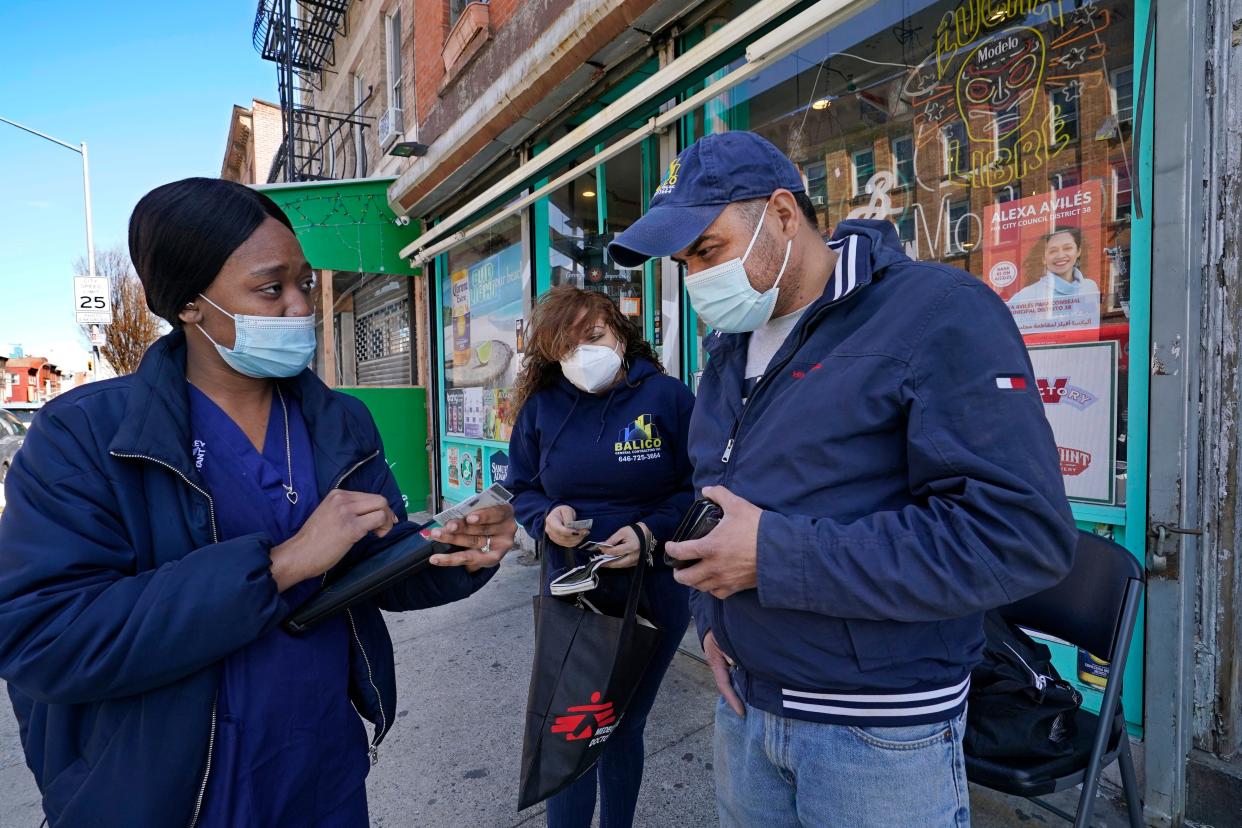 A health care worker, left, registers Immanuel Balico and his wife Nereyda Garcia for COVID-19 vaccinations on the street near a mobile vaccination van providing the vaccine in the Sunset Park neighborhood of Brooklyn, Monday, March 29, 2021, in New York. Balico and Garcia were getting the one-dose Johnson & Johnson vaccine through a partnership between NYC Test & Trace Corps and Mixteca, a community-based organization serving Spanish-speaking and indigenous Latin Americans in the area.