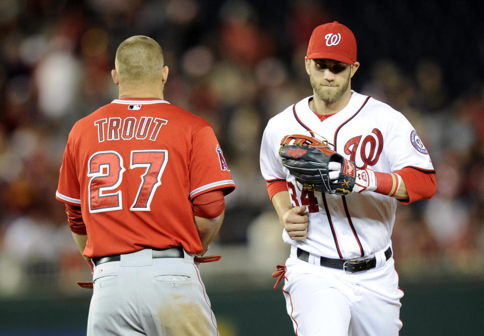 Washington Nationals left fielder Bryce Harper (34) runs from the field past Los Angeles Angels' Mike Trout (27) during the middle of the seventh inning of a baseball game, Monday, April 21, 2014, in Washington. The Angels won 4-2. (AP Photo/Nick Wass)