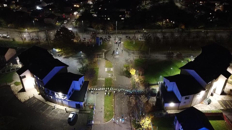 Drone footage from Niddrie shows a line of police officers with riot shields (PA)