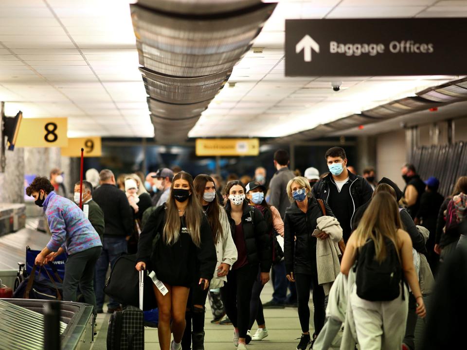 FILE PHOTO: Travelers wearing protective face masks to prevent the spread of the coronavirus disease (COVID-19) reclaim their luggage at the airport in Denver, Colorado, U.S., November 24, 2020.