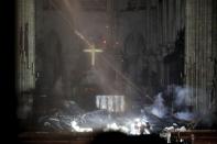 While much of what was inside the cathedral appeared to be damaged by smoke and ash, and embers still fell from the roof, the large cross in the front of the building was miraculously captured still standing and lit up amongst the darkness on Tuesday.