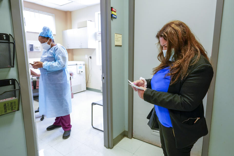 Angelita Ramos, right, goes over her vaccination card while waiting for licensed practical nurse Karja Austin to inoculate her with the second dose of the Moderna COVID-19 vaccine, Wednesday, May 12, 2021, at the Joseph P. Addabbo Family Health Center in the Far Rockaway neighborhood of the Queens borough of New York. (AP Photo/Mary Altaffer)