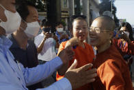 Theary Seng, right, a Cambodian-American lawyer, dressed in a prison-style orange outfit, greets her supporters as she arrived at Phnom Penh Municipal Court in Phnom Penh, Cambodia, Tuesday, Jan. 4, 2022. Cambodian security forces on Tuesday briefly detained Theary, a prominent rights activist, as she walked barefoot near the prime minister’s residence in Phnom Penh, wearing the orange outfit and Khmer Rouge-era ankle shackles. She was released, shortly afterwards, and arrived at the Phnom Penh court for the resumption of her trial on treason charges. (AP Photo/Heng Sinith)