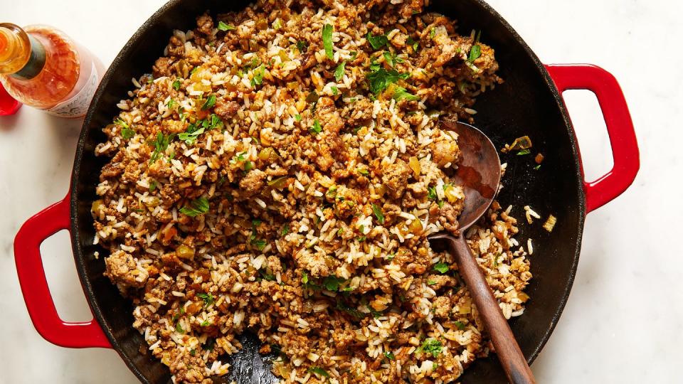 dirty rice topped with chopped parsley in a red cast iron pan