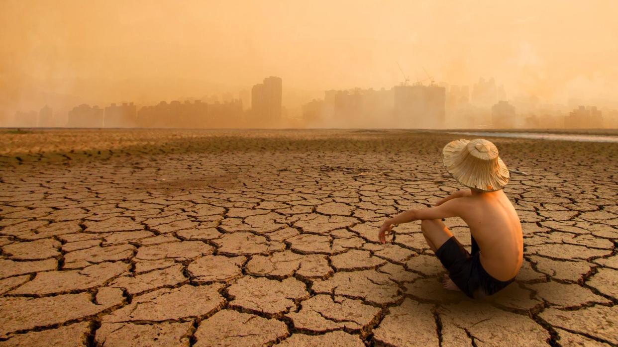 Persona en una tierra árida frente a una ciudad.