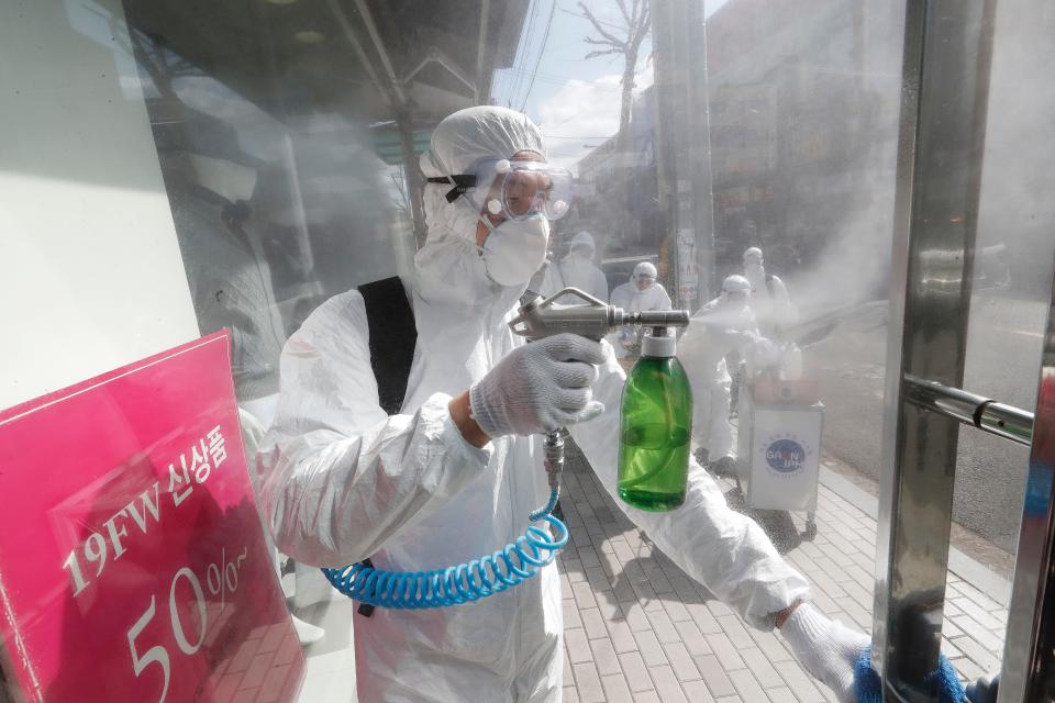 A worker wearing protective gears sprays disinfectant as a precaution against the coronavirus at a shopping street in Seoul, South Korea, Thursday, Feb. 27, 2020. The new illness persists in the worst-hit areas and spreads beyond borders. (AP Photo/Ahn Young-joon)