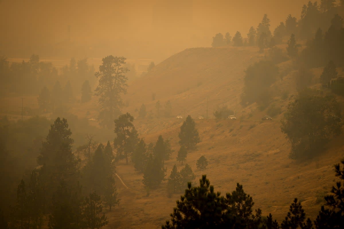 Smoke from wildfires fills the air as motorists travel on a road on the side of a mountain, in Kelowna, British Columbia (AP)