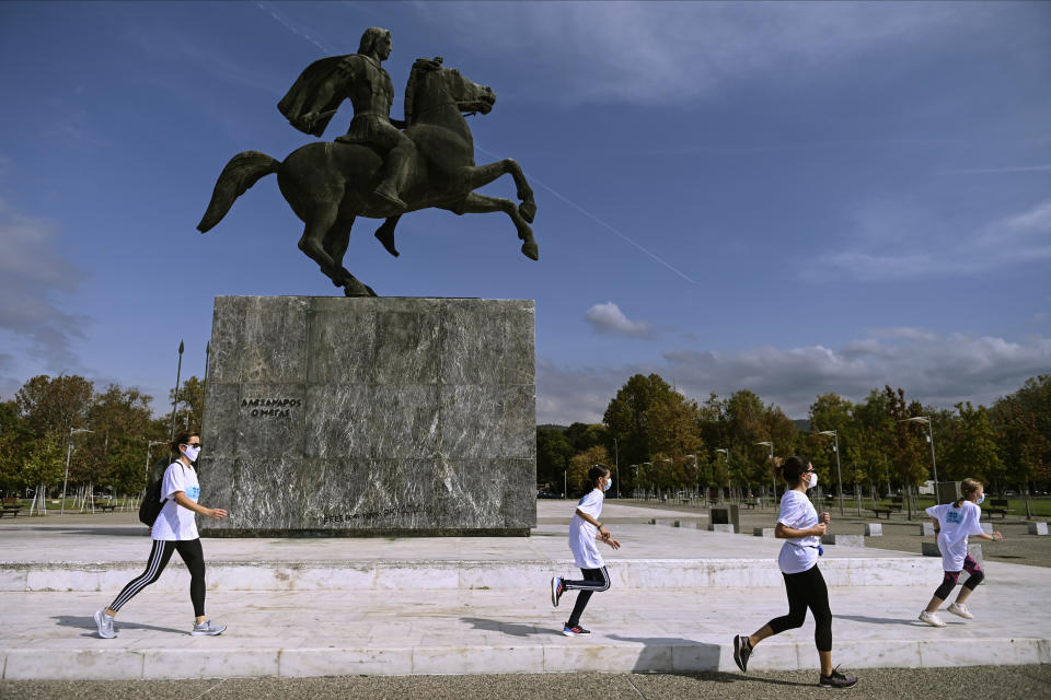 People participate in an event, organized by the local medical association, to support the use of protective masks, in front of a statue of Alexander the Great, in the northern city of Thessaloniki, Greece, Saturday, Oct. 3, 2020. Lung doctors staged a public demonstration of the benefits of face masks by fast-walking a distance of 2 kilometers (1.25 miles) through the city center aiming to debunk a widely-circulated rumor by anti-mask conspiracy theorists that wearing one left people short of breath. (AP Photo/Giannis Papanikos)