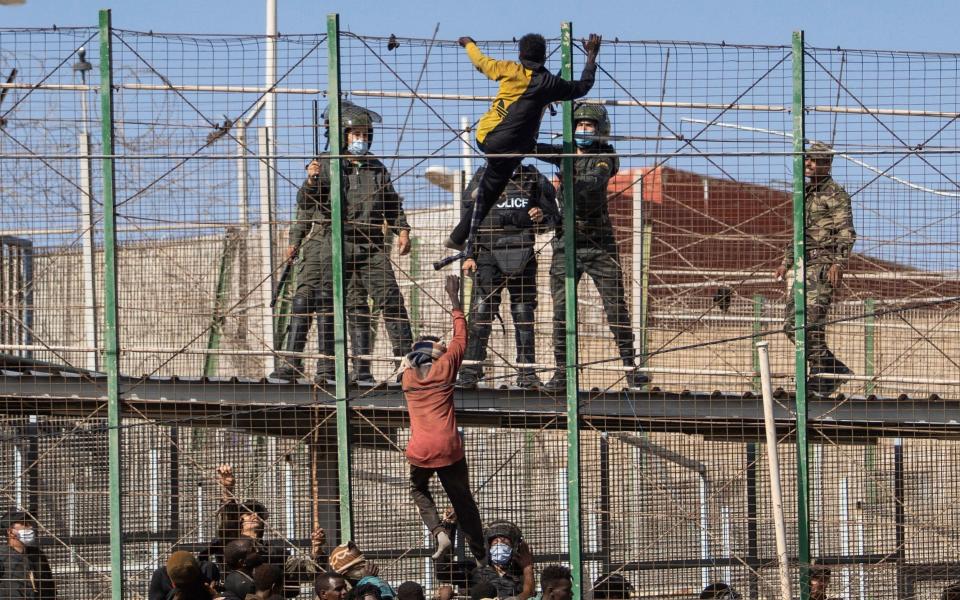 Migrants climb the six-metre-high double fence - Javier Bernardo/AP