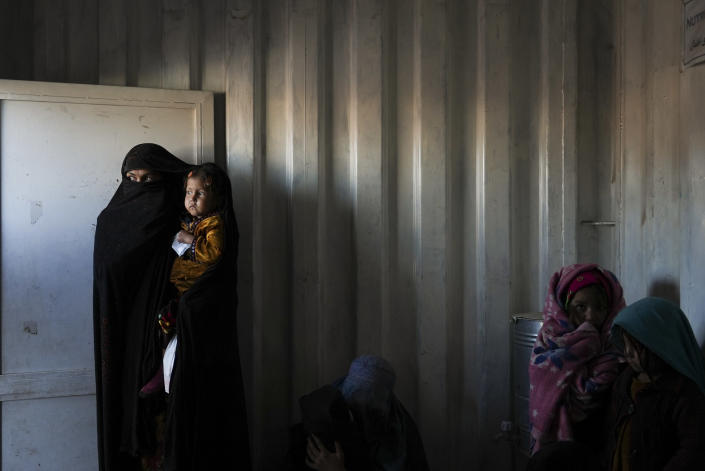 Afghan women wait in the makeshift clinic organized by World Vision at a settlement near Herat, Afghanistan, Dec. 16, 2021. The aid-dependent country’s economy was already teetering when the Taliban seized power in mid-August amid a chaotic withdrawal of U.S. and NATO troops. The consequences have been devastating for a country battered by four decades of war, a punishing drought and the coronavirus pandemic. (AP Photo/Mstyslav Chernov)