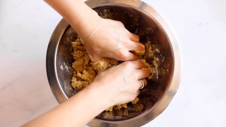 hands working dough in bowl 