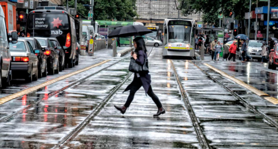 Woman walking in rain with umbrella 