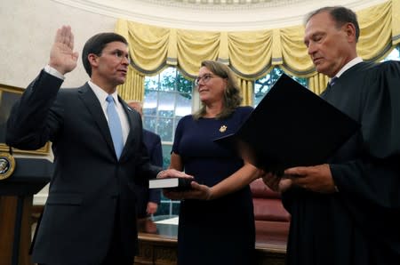 Mark Esper is sworn in as the new Secretary of Defense by Associate Justice Samuel Alito as Esper's wife Leah Esper holds the Bible as U.S. President Donald Trump looks on behind them in the Oval Office of the White House in Washington