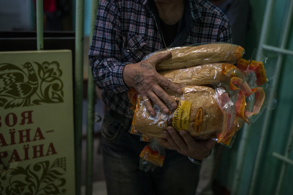 Volunteers distribute bread rations to civilians at a public school in Mykolaiv, Ukraine, Tuesday, Oct. 25, 2022. Mykolaiv residents pick up bread from the only food distribution point in Varvarivka, a Mykolaiv district where thousands of people live. One person is allowed to receive free bread just once in three days. (AP Photo/Emilio Morenatti)