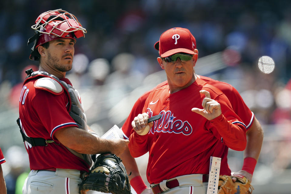Philadelphia Phillies interim manager Rob Thomson (59) and catcher J.T. Realmuto (10) talk on the mound during a pitching change in the eighth inning of a baseball game against the Atlanta Braves, Wednesday, Aug. 3, 2022, in Atlanta. (AP Photo/John Bazemore)