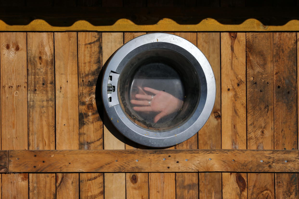 A woman is seen through a glass door of a washing machine that has been used as a window of a makeshift office at an environment-friendly beachfront cafe in Gaza on July 8, 2021. REUTERS/Ibraheem Abu Mustafa