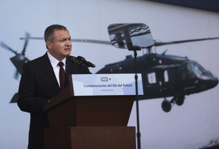 A man speaks at a podium in front of an image of a helicopter.