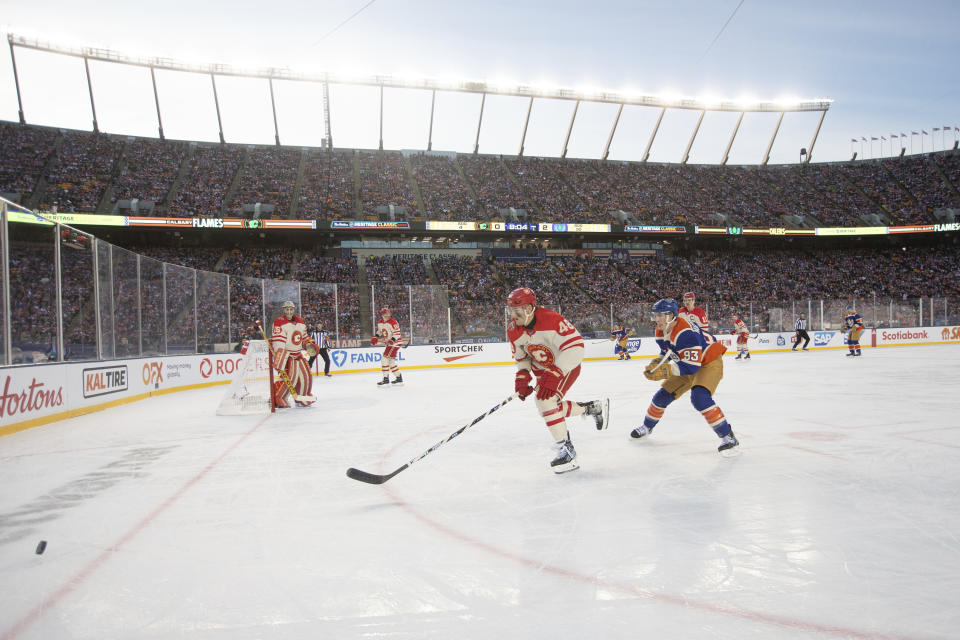 Calgary Flames' Dennis Gilbert (48) and Edmonton Oilers' Ryan Nugent-Hopkins (93) skate for the puck during first-period NHL Heritage Classic outdoor hockey game action in Edmonton, Alberta, Sunday, Oct. 29, 2023. (Jason Franson/The Canadian Press via AP)