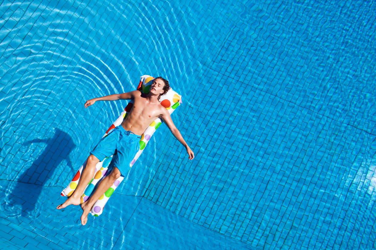 Guy laying on a pool float over water.