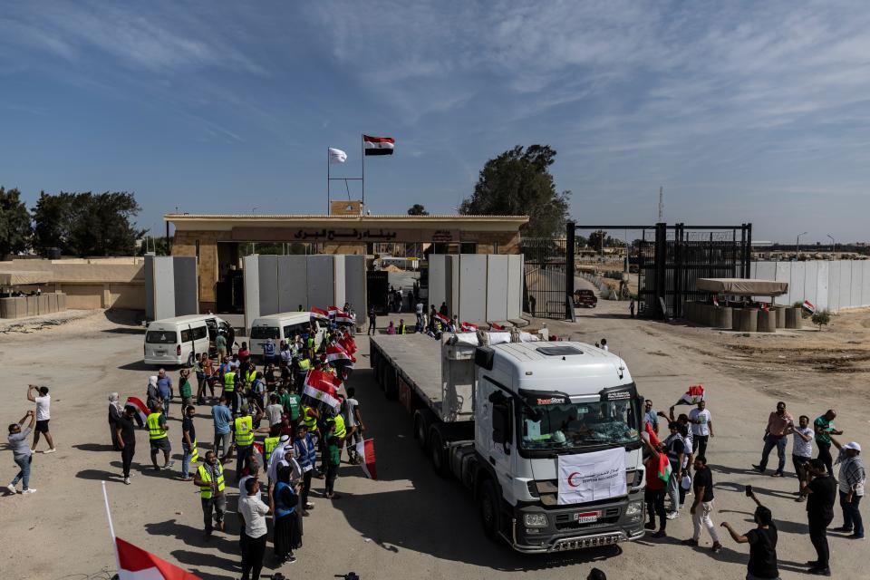 NORTH SINAI, EGYPT - OCTOBER 21: Volunteers and NGOs staff celebrate after unloading aid supplies and returning to Egyptian side of border on October 21, 2023 in North Sinai, Egypt. The aid convoy, organized by a group of Egyptian NGOs, set off Saturday 14th October from Cairo for the Gaza-Egypt border crossing at Rafah. A week of tortuous negotiations followed about when the border, controlled by Egypt on one side and Hamas on the other, would be opened, until the first trucks were admitted on 21st October. (Photo by Mahmoud Khaled/Getty Images)