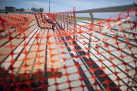 A man sunbathes on the boardwalk next to orange mesh surrounding a bench in order to maintain proper social distance, Wednesday, May 27, 2020, in Long Beach, N.Y. The beach on Long Beach is open only to residents. Long Island has become the latest region of New York to begin easing restrictions put in place to curb the spread of the coronavirus as it enters the first phase of the state's four-step reopening process. (AP Photo/Mary Altaffer)