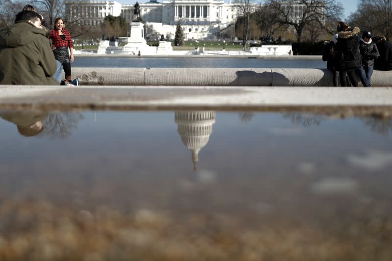 A woman poses for photos along the reflecting pool at the U.S. Capitol on the National Mall in Washington