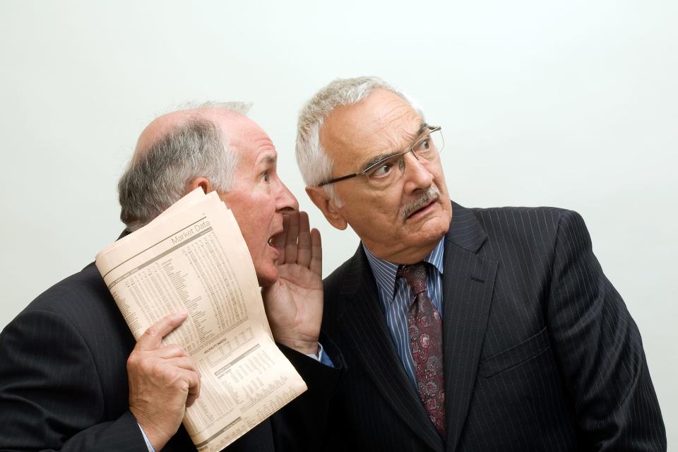 Two businessmen whisper suspiciously, one holding a newspaper - insider trading