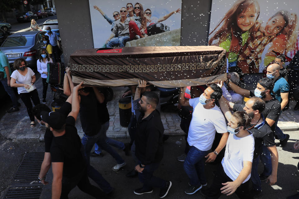 Mourners carry the coffin of Ibrahim Harb, 35, who was critically injured in the massive explosion at Beirut's port last year and who died on Monday nearly 14 months after the blast, as other throw rice during his funeral procession in Beirut, Lebanon, Tuesday, Sept. 28, 2021. On Aug. 4, 2020, hundreds of tons of ammonium nitrate, a highly explosive material used in fertilizers, ignited after a massive fire at the port. The death brings to at least 215 the number of people who have been killed by the blast, according to official records. (AP Photo/Hussein Malla)