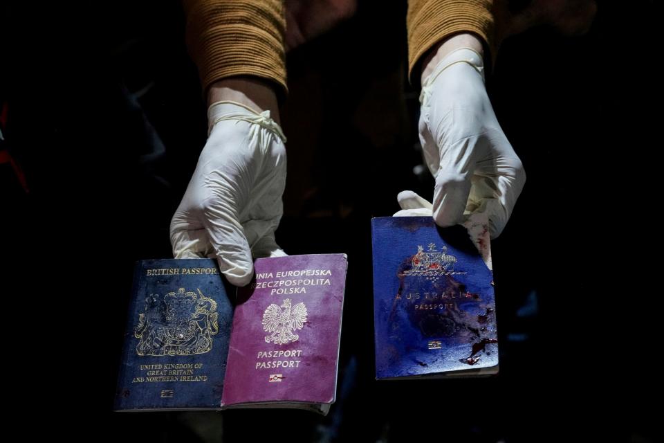 A man displays blood-stained British, Polish, and Australian passports after an Israeli airstrike