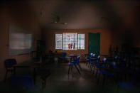 A classroom sits empty at La Ilusion community school, closed amid the COVID-19 pandemic, where girls play basketball outside in La Ilusion, Chiapas state, Mexico, Wednesday, Sept. 19, 2020. Amid the new coronavirus pandemic, Mexican education officials recently said that enrollment for the new school year was down about 10%, but some teachers warn that many students enrolled out of habit, but aren't participating. (AP Photo/Eduardo Verdugo)