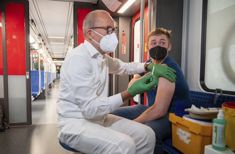 Christian Gravert, left, chief medical officer of the Deutsche Bahn, vaccinates a man with the Johnson & Johnson vaccine in a special train of the public transport S-Bahn, in which vaccination against COVID-19 are offered, in Berlin, Germany, Aug. 30, 2021. (Christophe Gateau/dpa via AP)