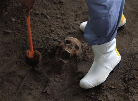 A police officer excavates a human skull at a construction site in the former war zone in Mannar, about 327 km (203 miles) from the capital Colombo, January 16, 2014. REUTERS/Dinuka Liyanawatte