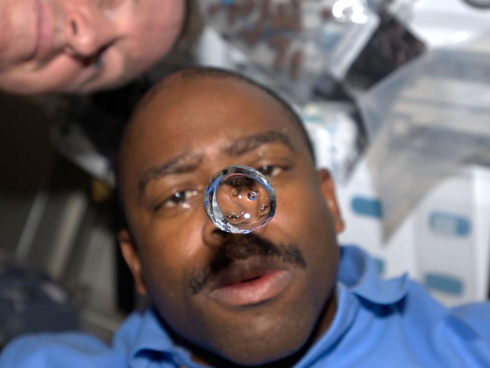 A water bubble floats in front of NASA Leland Melvin on the space shuttle Atlantis
