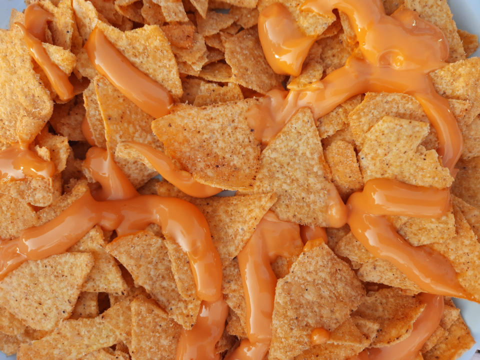 Close-up view of tortilla chips covered in melted cheese