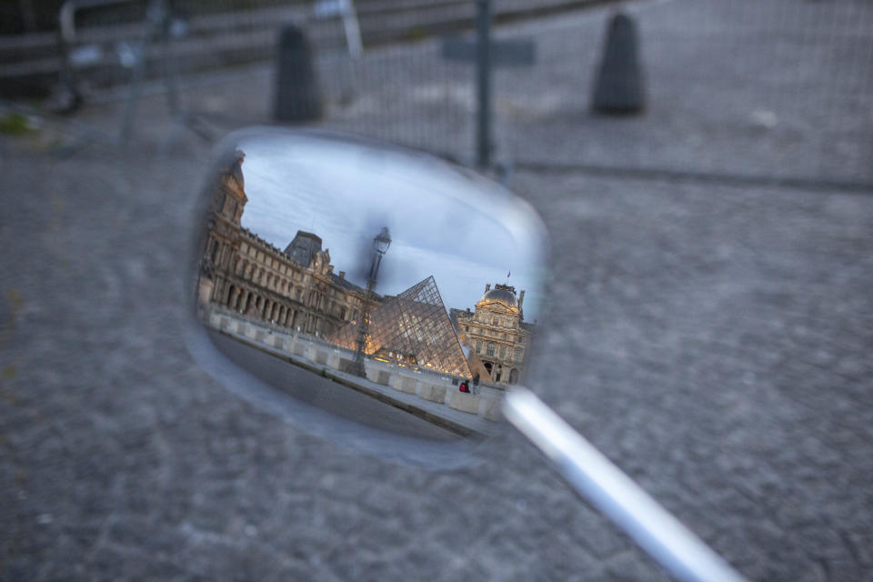 The mostly deserted courtyard of the Louvre Museum which is temporarily closed is seen in a mirror reflection on Saturday, May 2, 2020, in Paris. France continues to be under an extended stay-at-home order until May 11 in an attempt to slow the spread of the COVID-19 pandemic. (AP Photo/Rafael Yahgobzadeh)