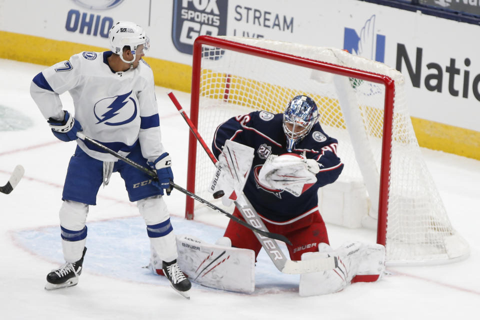 Columbus Blue Jackets' Elvis Merzlikins, right, of Latvia, makes a save as Tampa Bay Lightning's Mathieu Joseph looks on during the first period of an NHL hockey game Saturday, Jan. 23, 2021, in Columbus, Ohio. (AP Photo/Jay LaPrete)