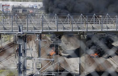 Tires set into fire by workers operating on the MyFerryLink car and passenger ferry boats burn on the tracks at the entrance of the Eurotunnel Channel Tunnel linking Britain and France in Coquelles near Calais, northern France, June 30, 2015. REUTERS/Vincent Kessler