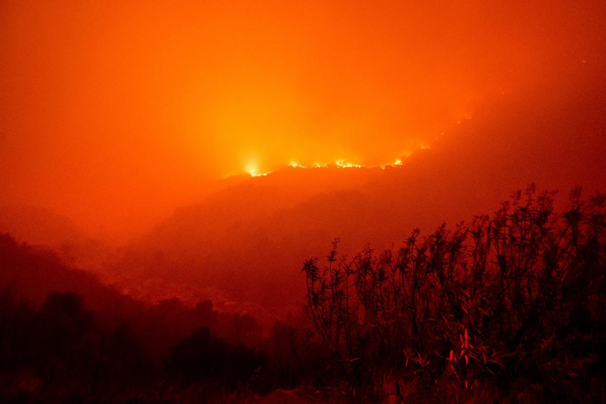 Flames from the KNP Complex Fire burn along a hillside above the Kaweah River in Sequoia National Park, Calif., on Tuesday, Sept. 14, 2021. The blaze is burning near the Giant Forest, home to more than 2,000 giant sequoias. 