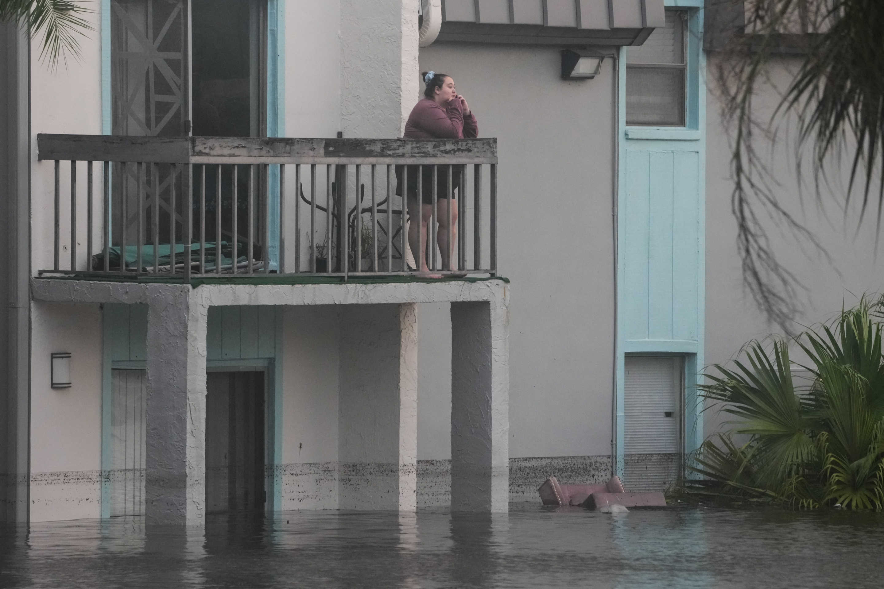 A woman watches from her second floor balcony as residents of an apartment complex are rescued due to Hurricane Milton on October 10, 2024 in Clearwater, Florida. (Bryan R. Smith/AFP via Getty Images)