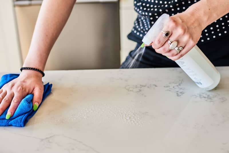 women spraying cleaner on kitchen counter