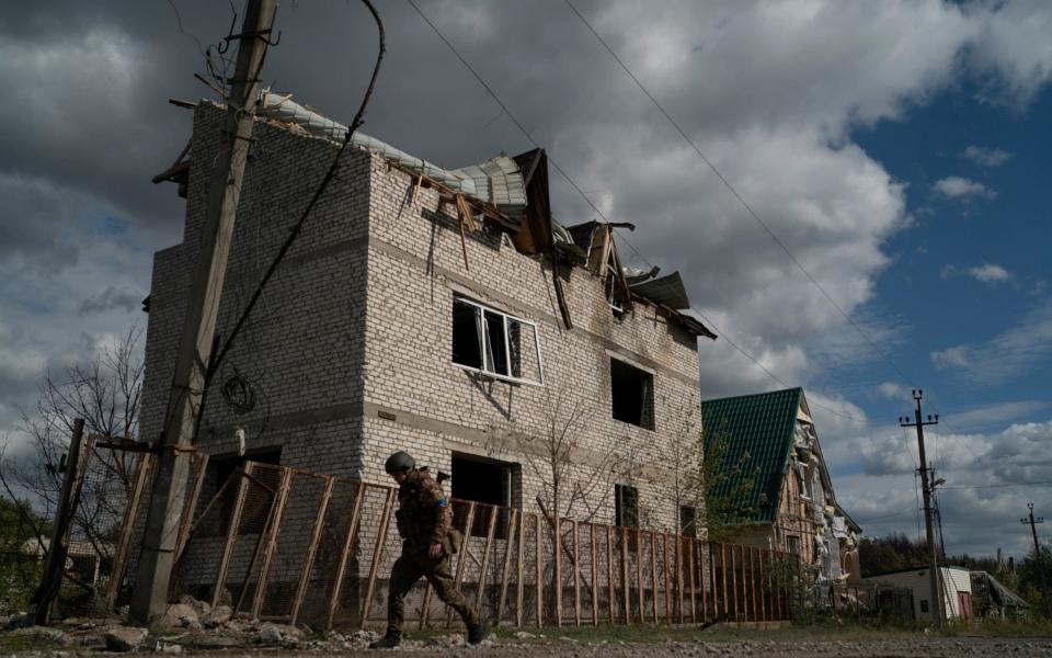 A Ukrainian soldier walks past a damaged building in the retaken village of Shchurove, Ukraine. - Leo Correa/AP