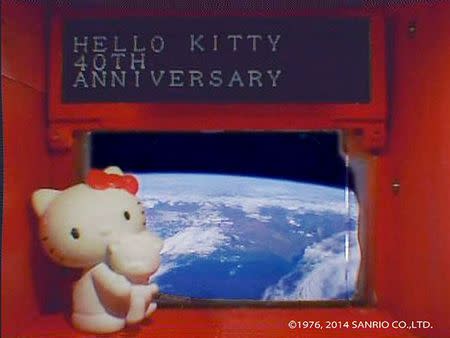 A 4-cm (1.6-inch) tall Hello Kitty figurine placed under a scrolling display in front of a window of the Hodoyoshi-3 satellite, is seen in what Sanrio Co. said is a still image from a video, made available to Reuters on August 14, 2014. REUTERS/Sanrio Co. ,Ltd./Handout via Reuters