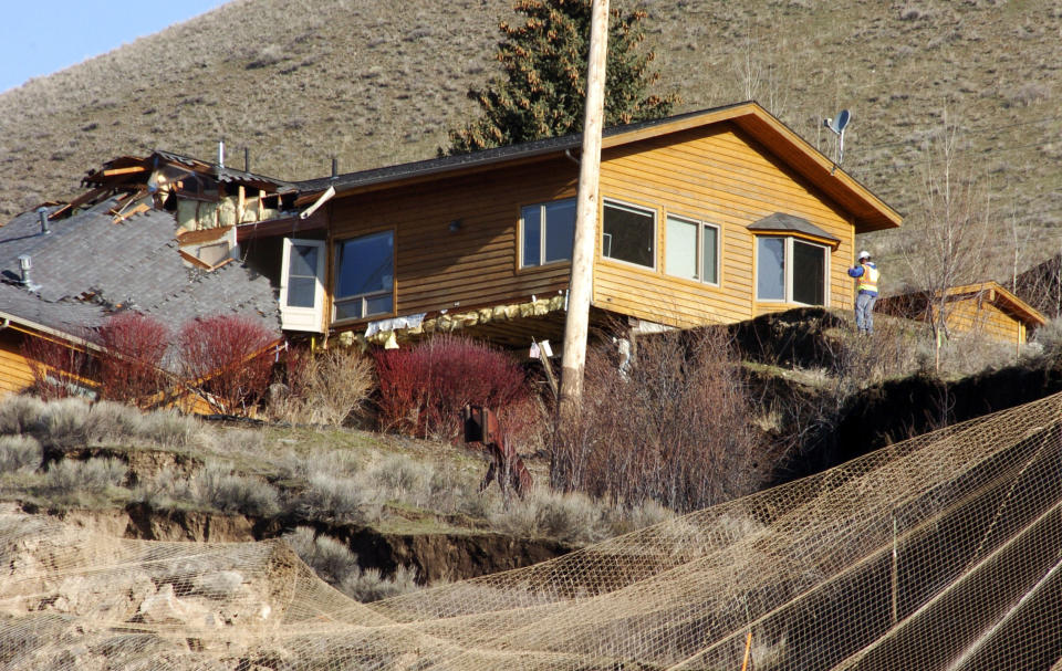 A worker inspects damage to a house at the top of a slow-motion landslide in Jackson, Wyo., on Saturday, April 19, 2014. No one can say when the mountainside collapsing into this Wyoming resort town will give way. But it appears increasingly likely that when it does, it's going to take a piece of Jackson with it. (AP Photo/Matthew Brown)