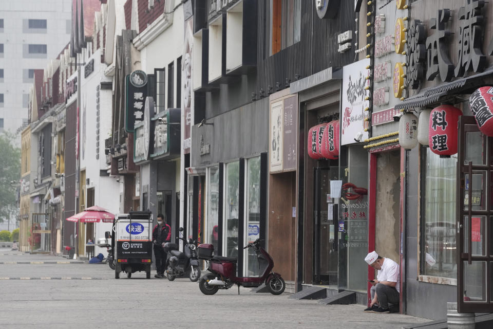 A chef sits outside a row of restaurants closed to dine in customers and only offering takeaway on Tuesday, May 10, 2022, in Beijing. China's capital began another round of three days of mass testing for millions of its residents Tuesday in a bid to prevent an outbreak from growing to Shanghai proportions. (AP Photo/Ng Han Guan)