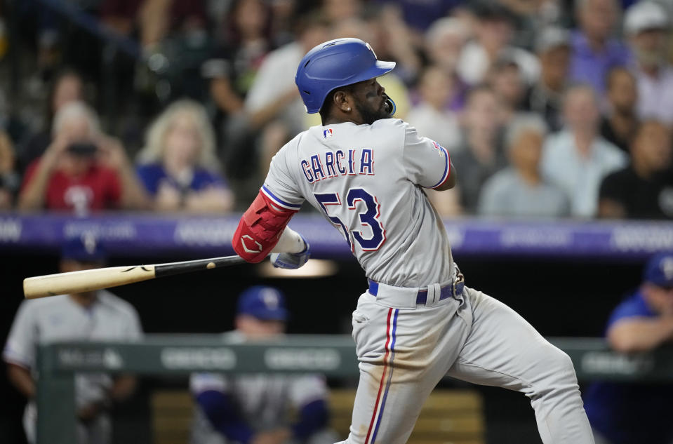 Texas Rangers' Adolis Garcia follows the flight of his RBI-double off Colorado Rockies starting pitcher German Marquez in the fifth inning of a baseball game Tuesday, Aug. 23, 2022, in Denver. (AP Photo/David Zalubowski)