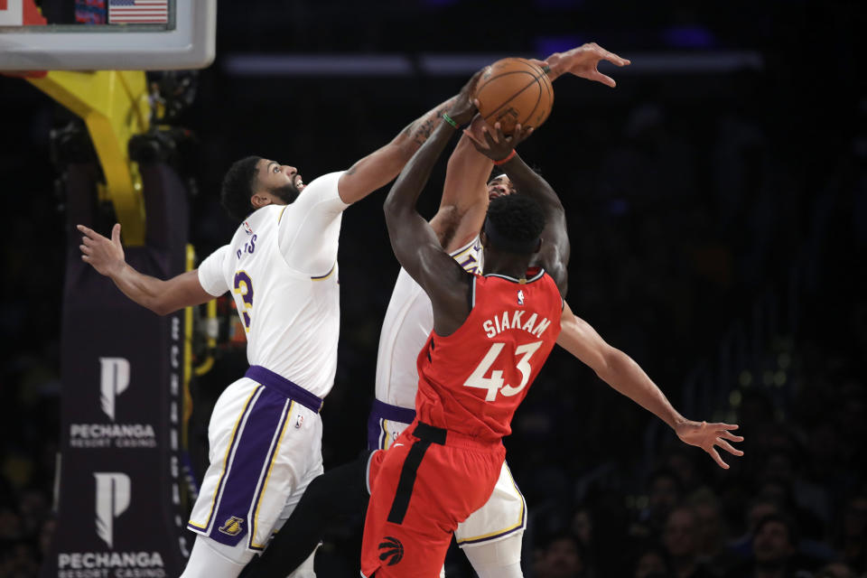 Los Angeles Lakers' Anthony Davis, left, blocks a shot from Toronto Raptors' Pascal Siakam (43) during the first half of an NBA basketball game Sunday, Nov. 10, 2019, in Los Angeles. (AP Photo/Marcio Jose Sanchez)