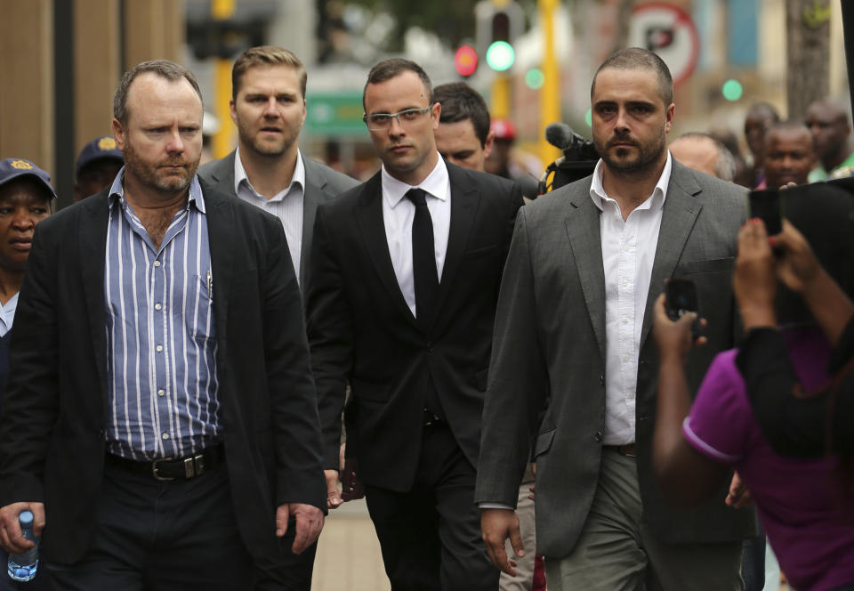 Oscar Pistorius, center, accompanied by his relatives, arrives at the high court in Pretoria, South Africa, Friday, March 28, 2014. The murder trial of Pistorius, who is charged with murder for the shooting death of his girlfriend, Reeva Steenkamp, on Valentines Day in 2013, has been delayed until April 7 because one of the legal experts who will assist the judge in reaching a verdict is sick, the judge said Friday. (AP Photo/Themba Hadebe)