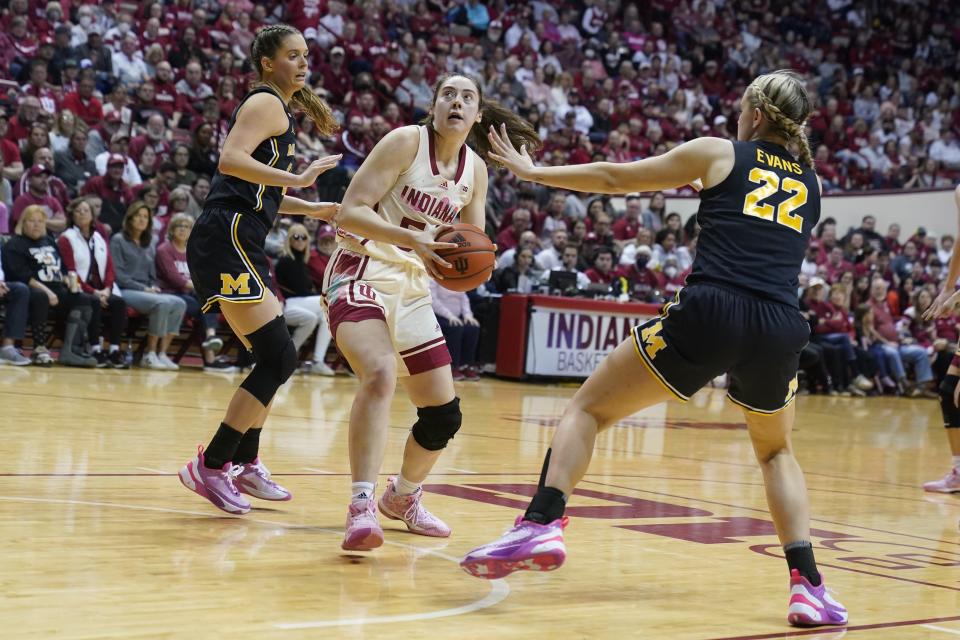 Indiana's Mackenzie Holmes (54) looks to the basket from between Michigan's Emily Kiser and Chyra Evans (22) during the second half of an NCAA college basketball game Thursday, Feb. 16, 2023, in Bloomington, Ind. (AP Photo/Darron Cummings)