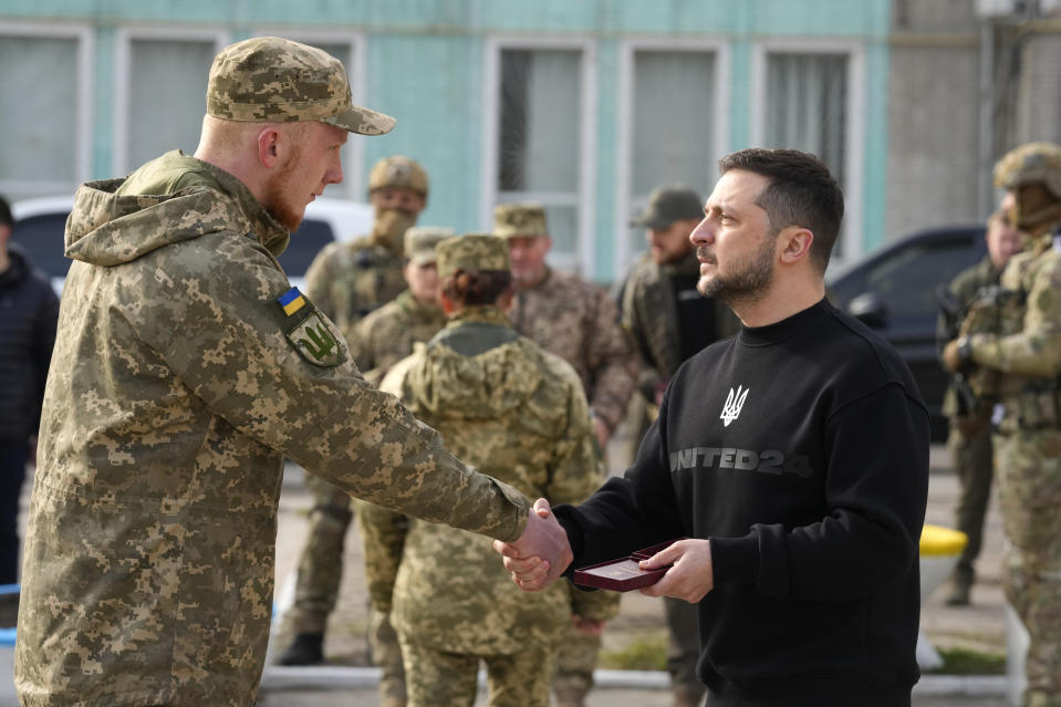 Ukrainian President Volodymyr Zelenskyy presents a medal to a serviceman in Okhtyrka in the Sumy region of Ukraine, Tuesday March 28, 2023. (AP Photo/Efrem Lukatsky)