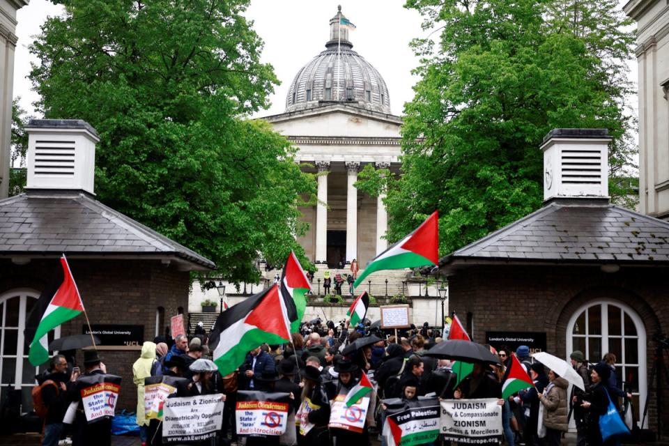 People hold placards and wave Palestinian flags as they take part in a demonstration in support to Palestinian people at University College London (AFP via Getty)